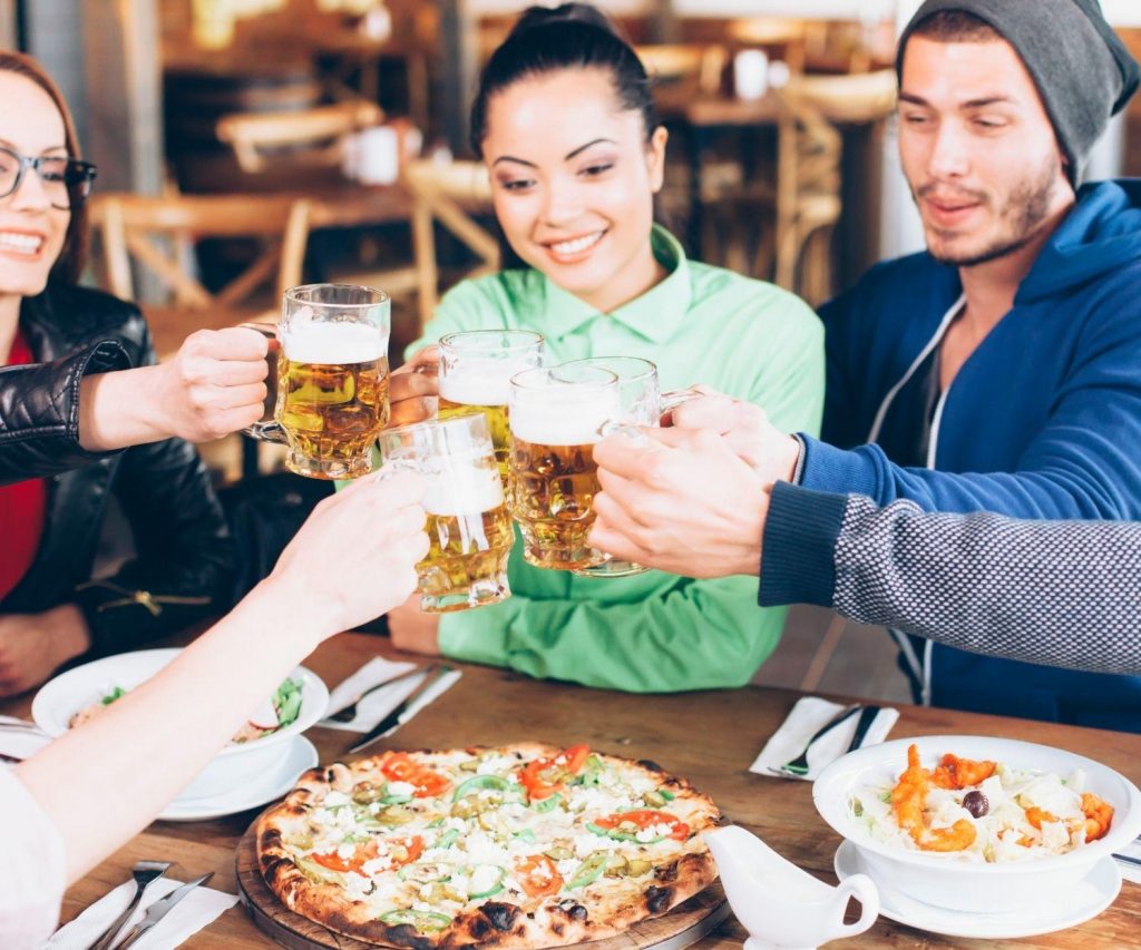 Multicultural group of friends sharing a meal together and toasting their beverages